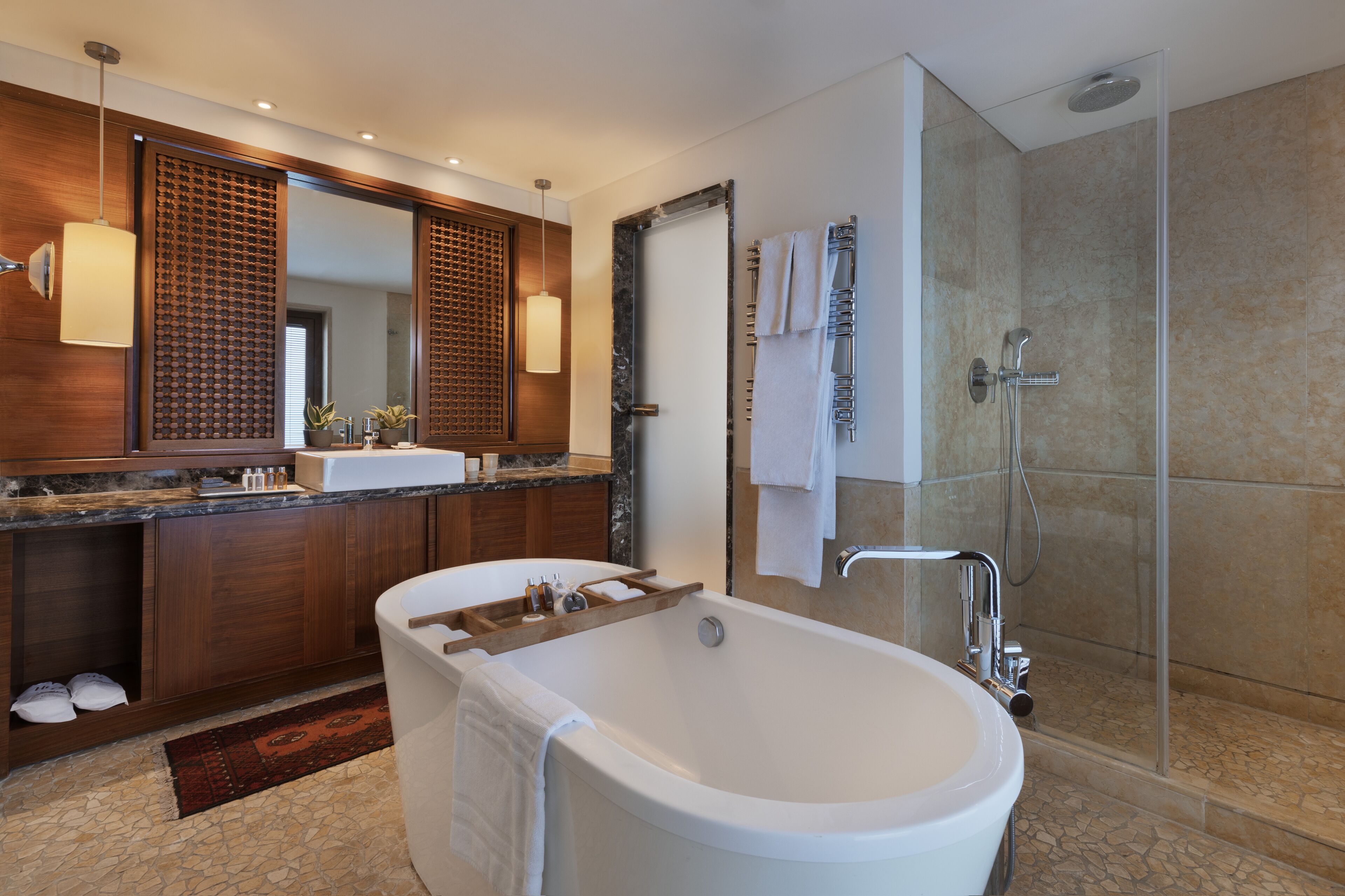 Un baño moderno con una bañera independiente, ducha con cerramiento de vidrio y un espejo grande sobre el lavamanos.