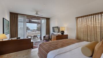 Una habitación de hotel con cama, escritorio, silla, televisor y ventana con cortinas.