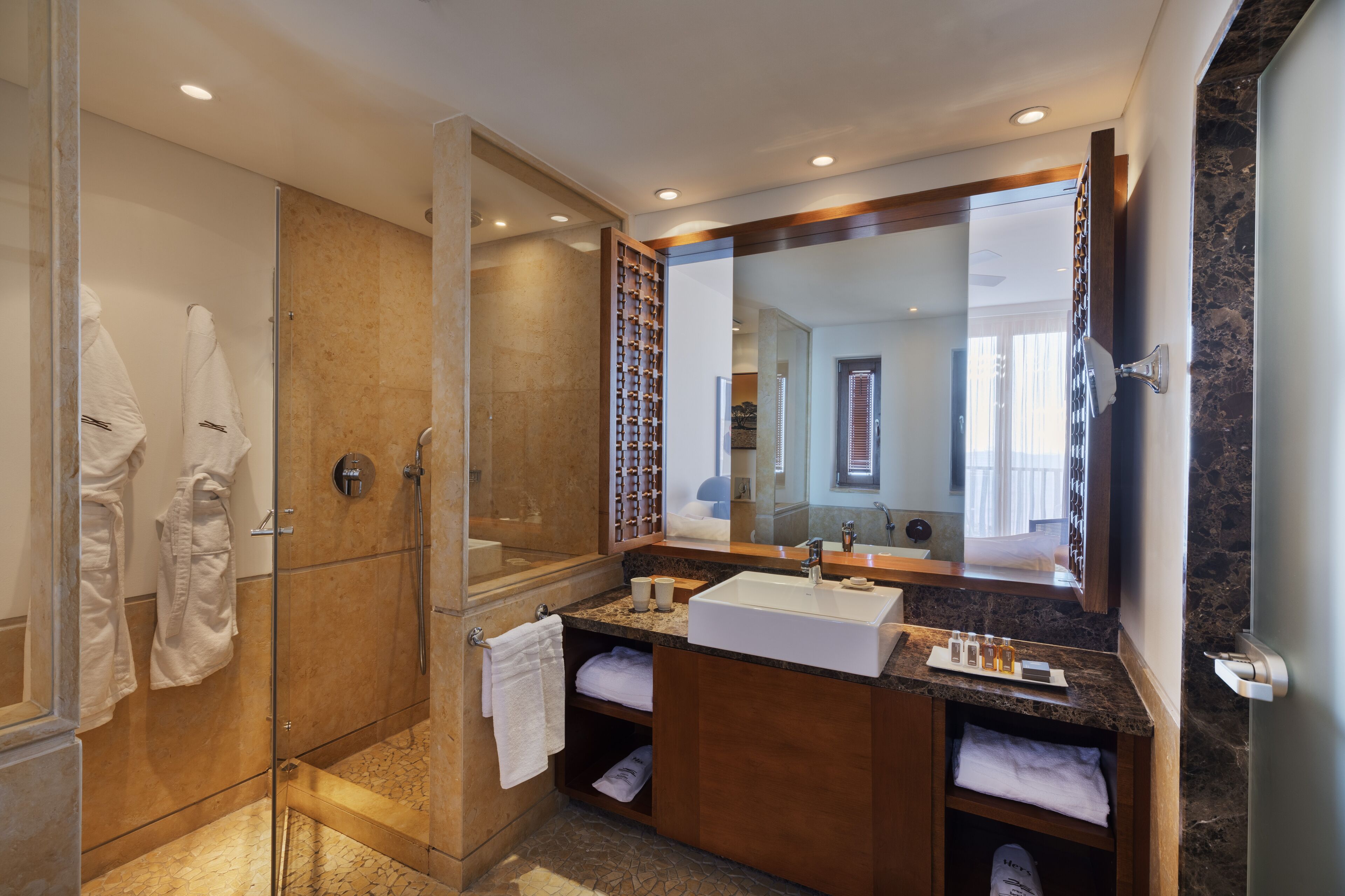 Un baño moderno con ducha envuelta en vidrio, un lavamanos grande y un mueble de tocador con espejo.