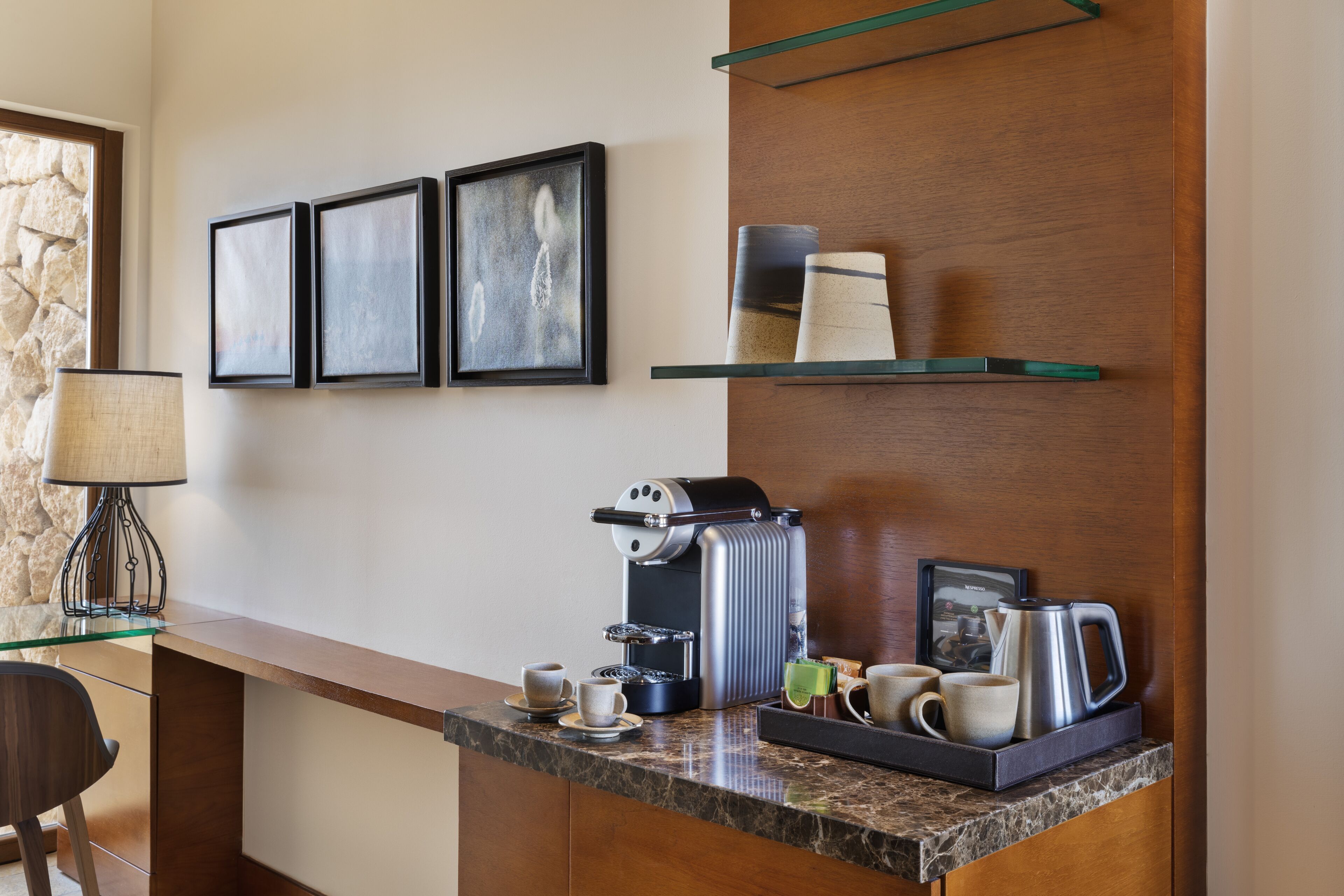 A modern kitchen with a coffee machine, cups, and a glass table.