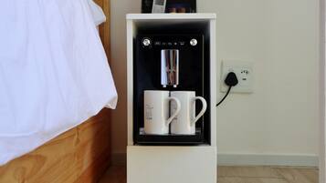 A white cabinet with a coffee machine and two white mugs labeled "The LAB" on a wooden bed.