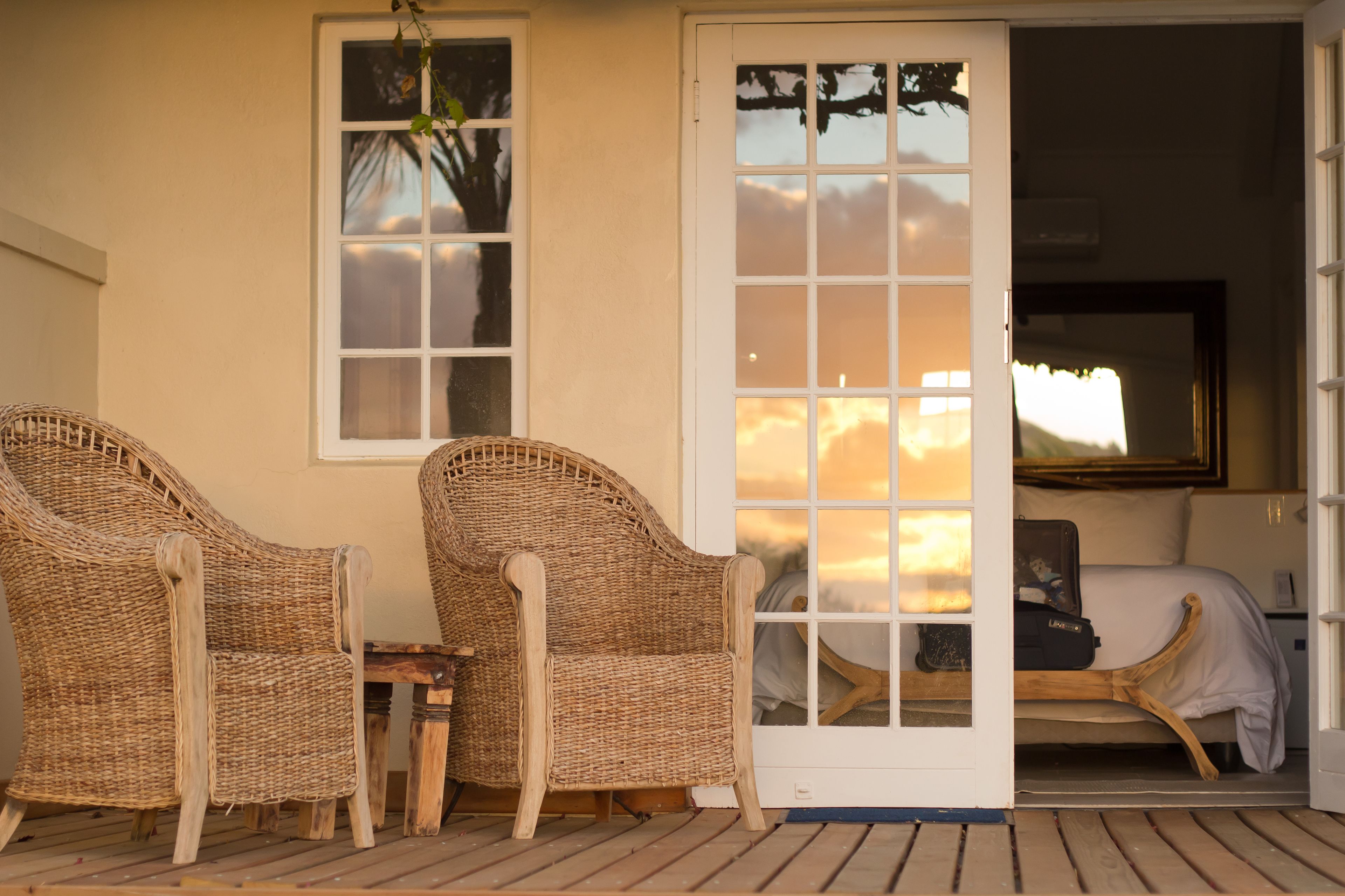 A room with a bed, a wicker chair, and a small table.