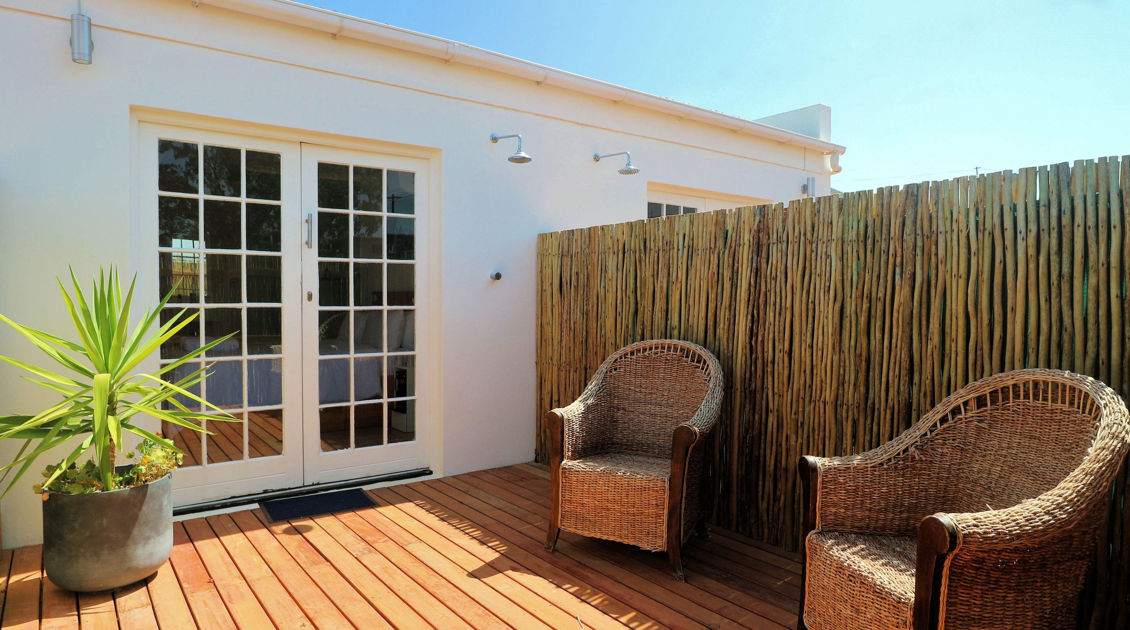 Una terraza de madera con dos sillones de mimbre y una planta en maceta.