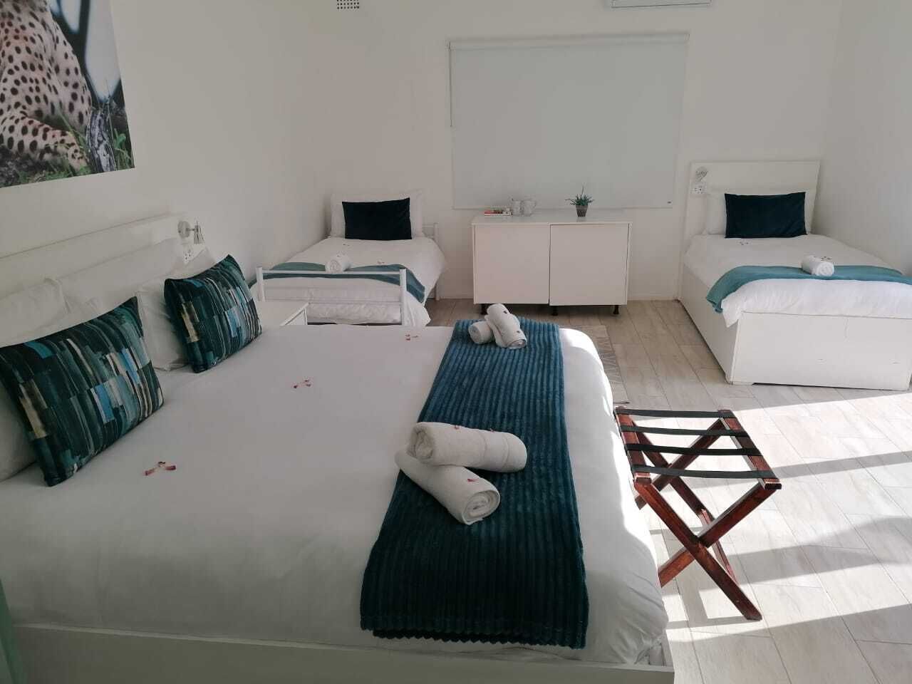 Ett hotellrum med två sängar, en vit byrå och ett litet bord.