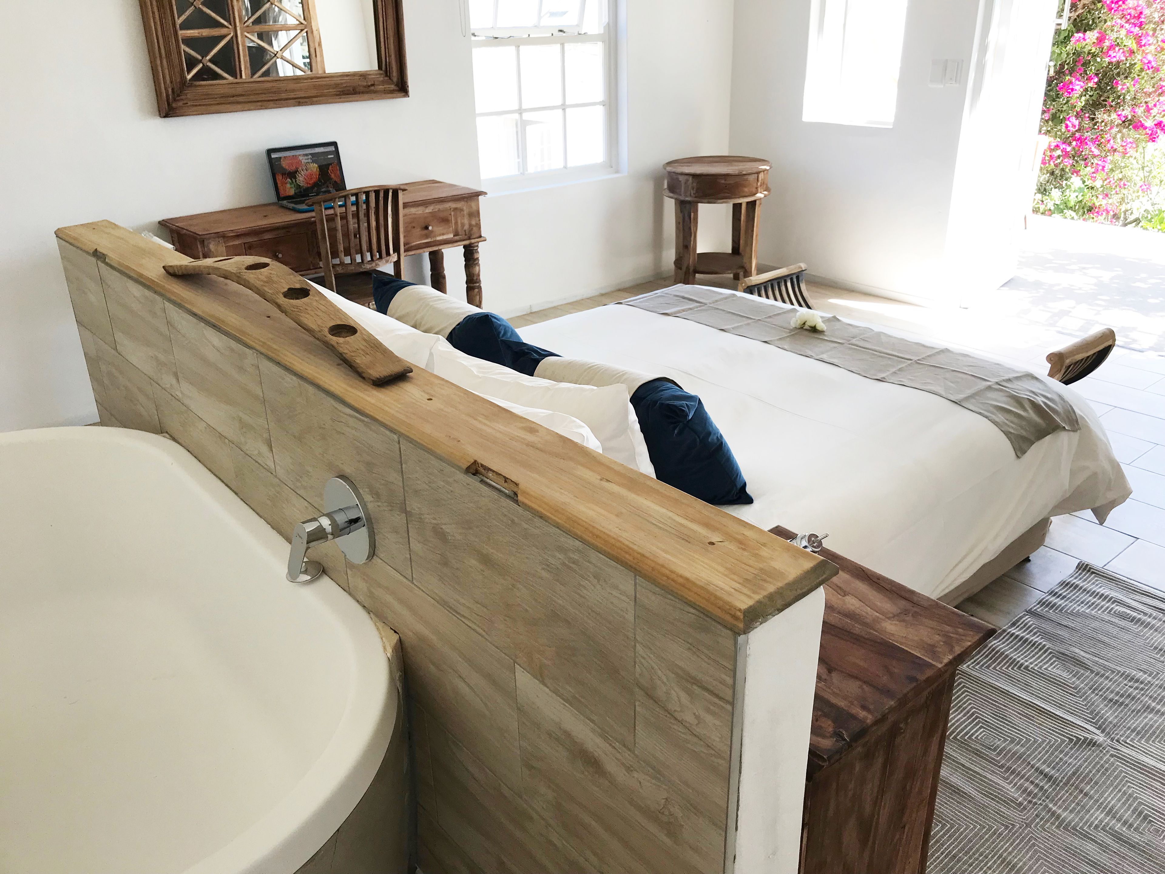 A modern bathroom with a wooden vanity, a large sink, and a bed with a wooden headboard.