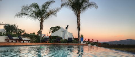 Una piscina al aire libre, sombrillas, sillones reclinables de piscina