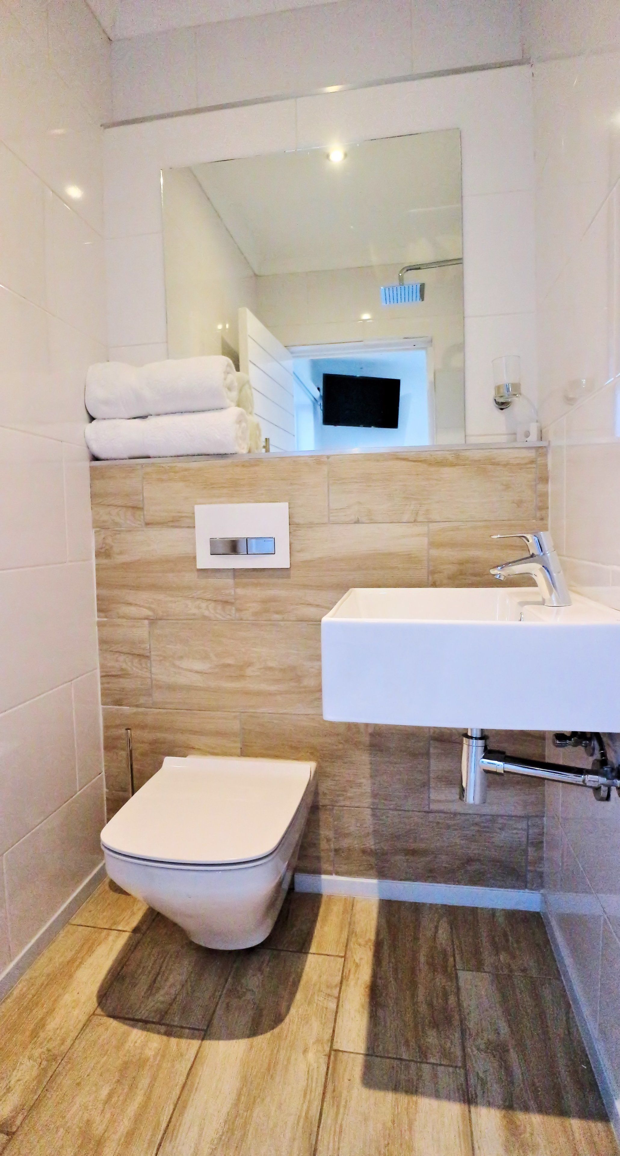 A modern bathroom with a toilet, sink, and mirror.