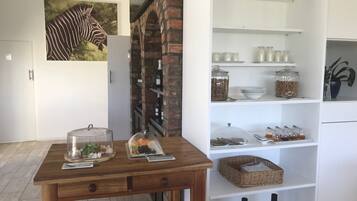 A modern kitchen with a brick wall, a zebra mural, and a wooden table with food and drink items.