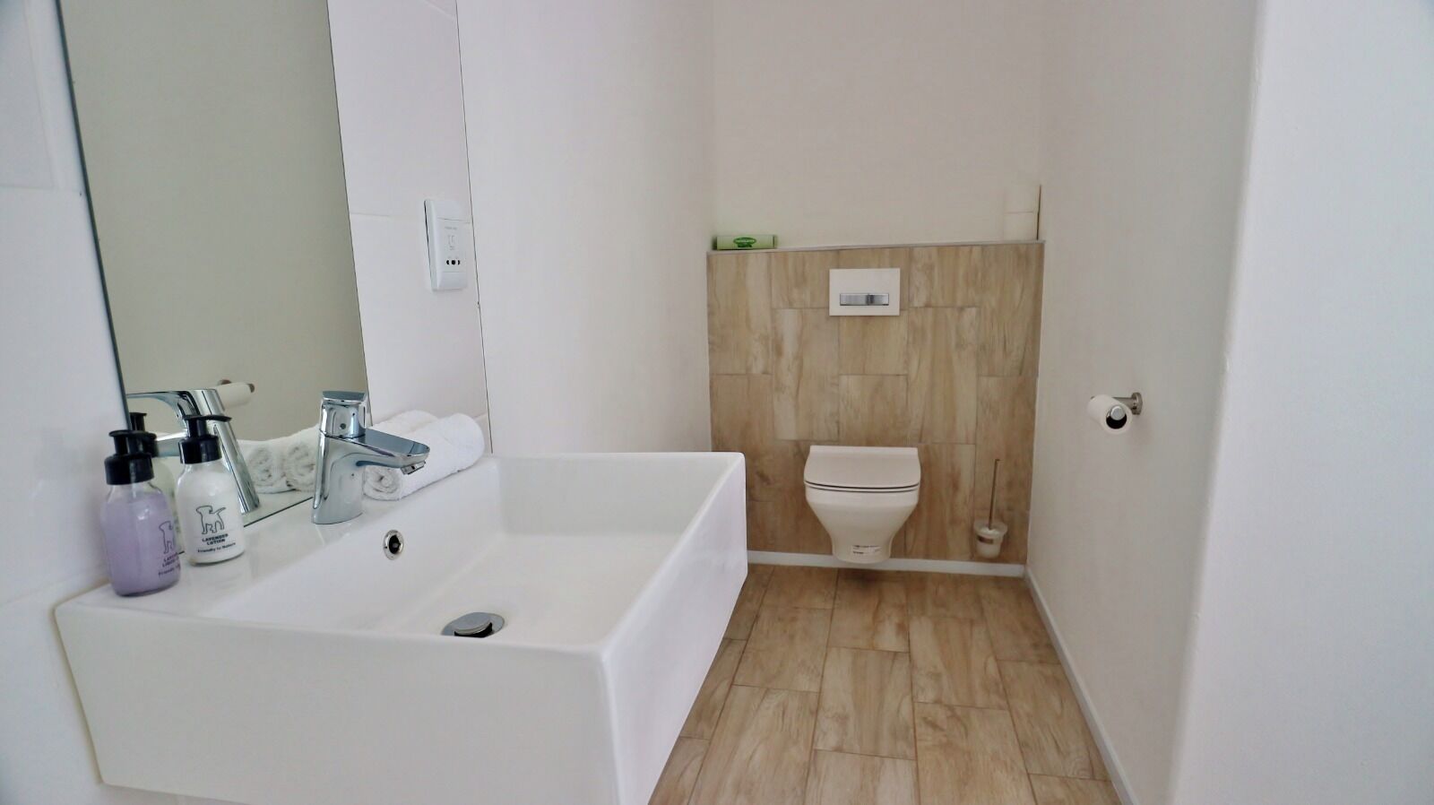 A small bathroom with a white sink, a mirror, and a toilet.
