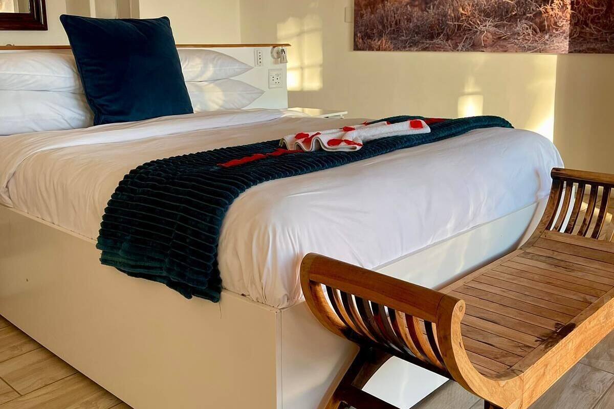 A bedroom with a bed, a wooden chair, a painting of a lion, and a white wall.