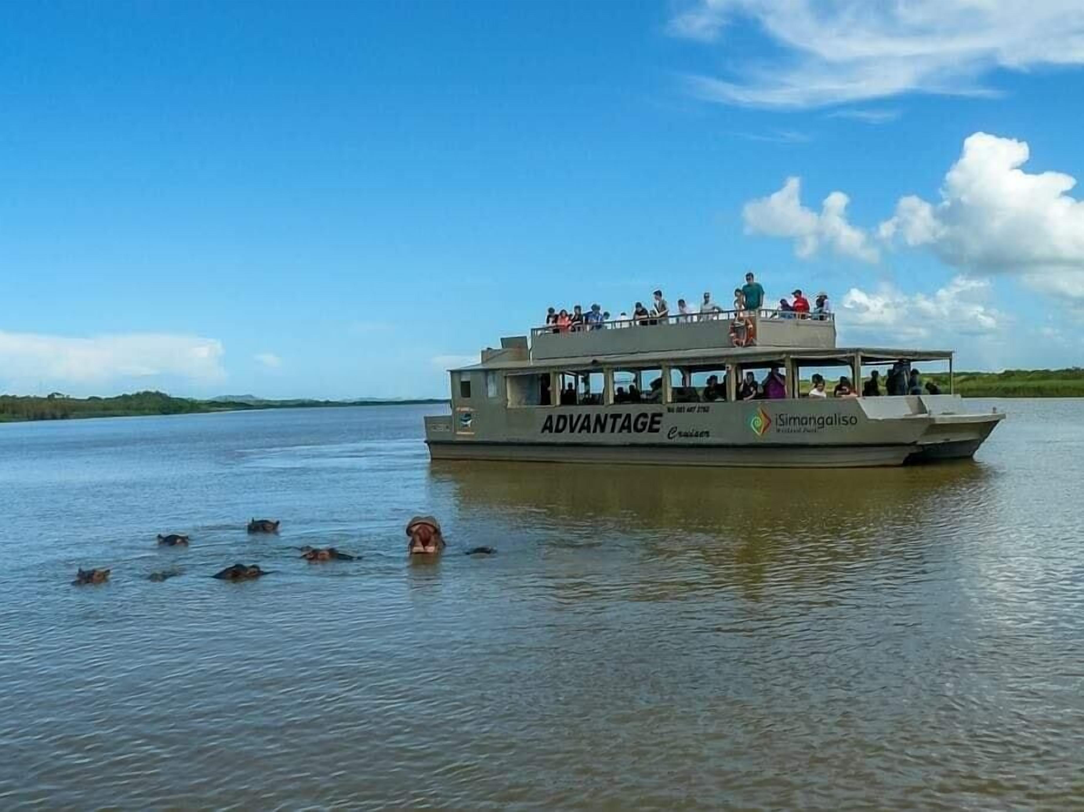 A boat with the name "ADVANTAGE" and "iSimangaliso" on its side, floating on calm water with several people on board.