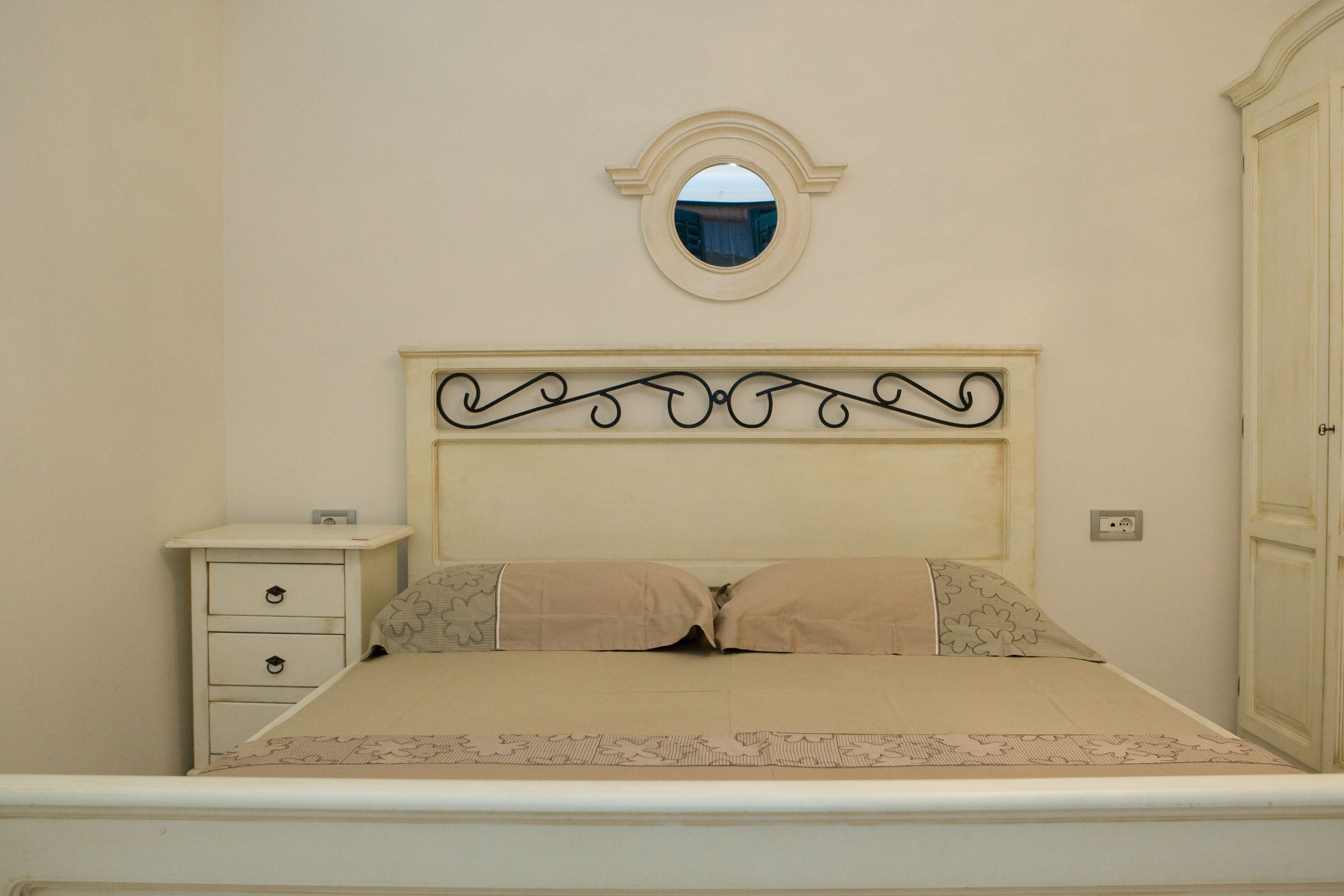 A bedroom with a bed, a nightstand, a mirror, and a wardrobe.