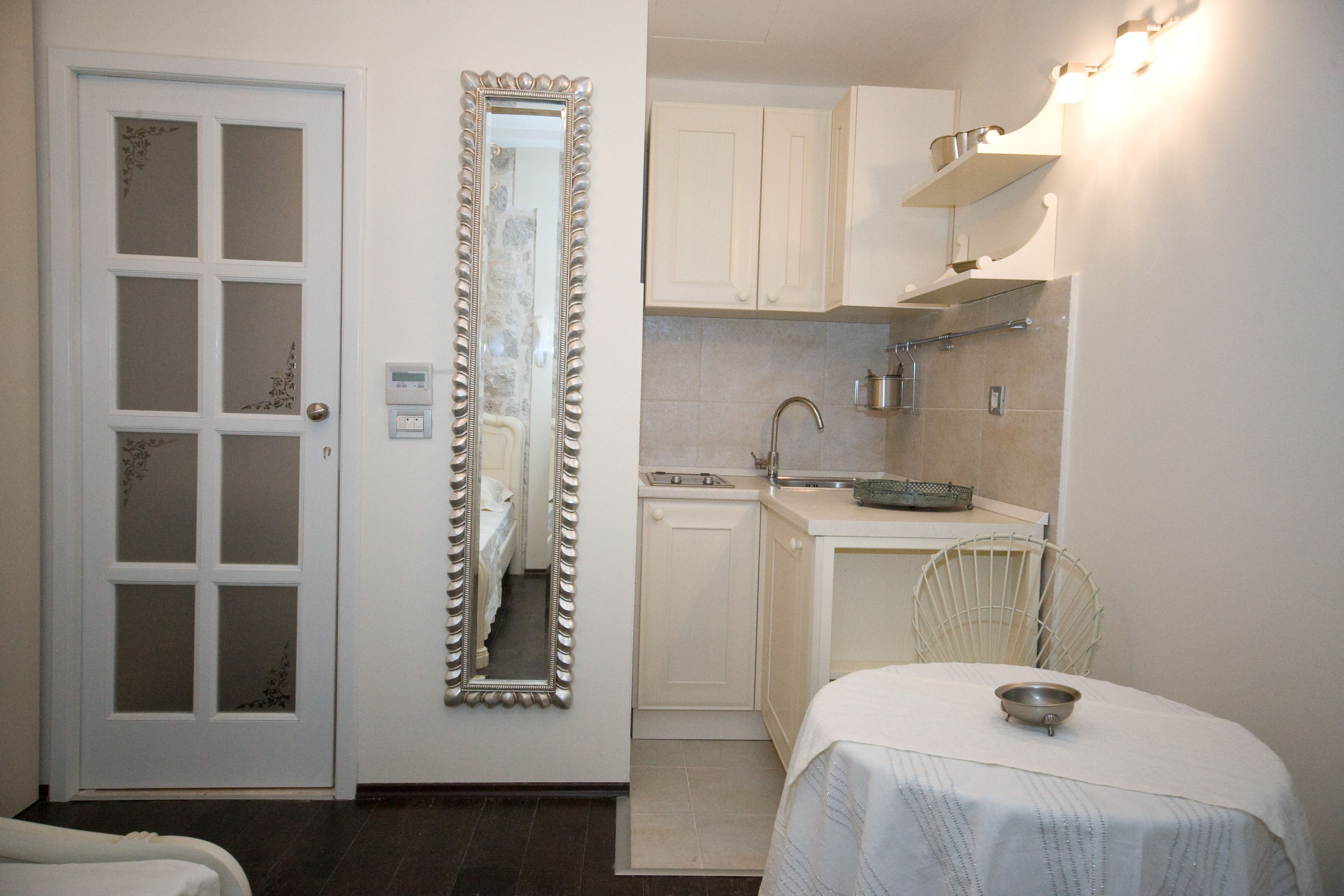 A compact kitchen with white cabinets, a sink, and a dining area with a table and chairs.