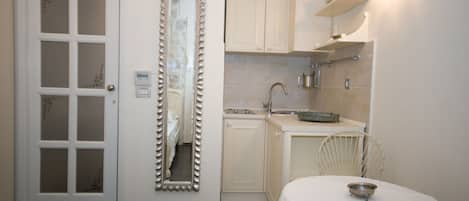 A compact kitchen with white cabinets, a sink, and a dining area with a table and chairs.