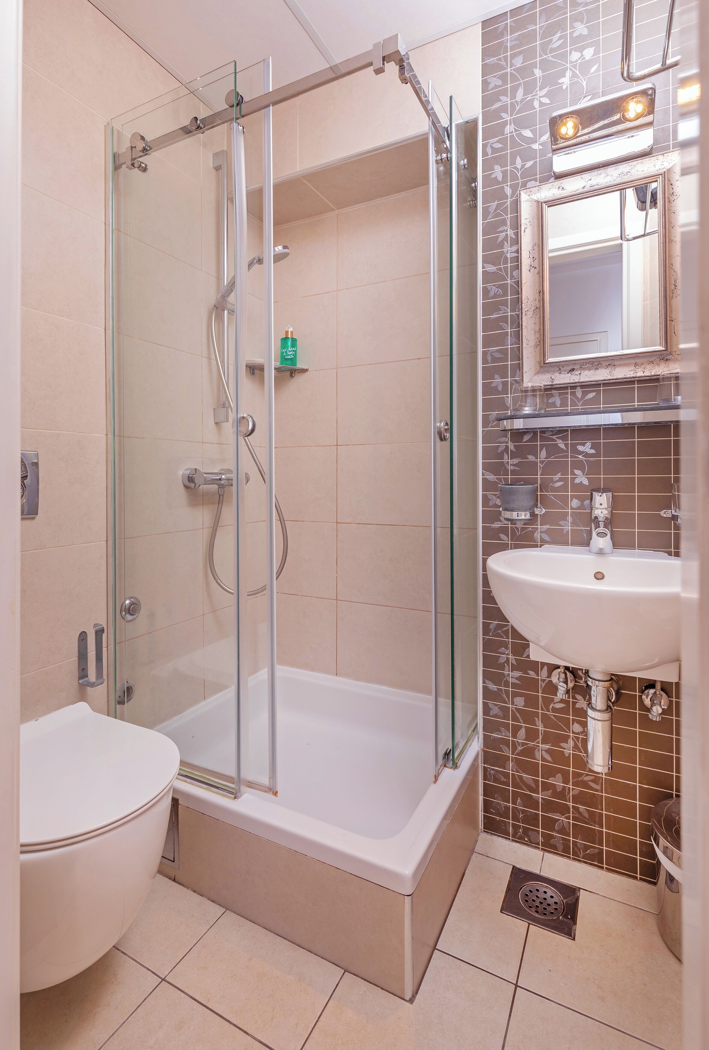 A bathroom with a glass-enclosed shower, a white sink, and a toilet.