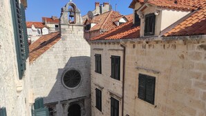Uma rua estreita com arquitetura tradicional, incluindo um campanário e um edifício com uma janela circular.