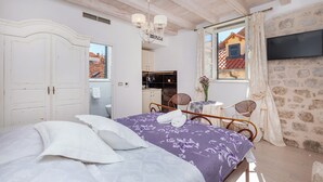 Quarto com cama, cômoda, televisão e vista para o exterior.