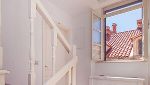 Uma escadaria com guarda-corpos brancos e degraus vermelhos, que leva a uma porta com janela acima.