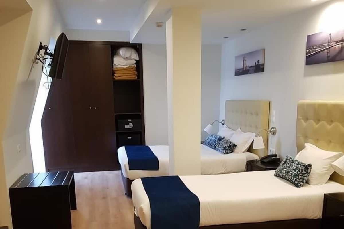 Habitación de hotel con dos camas, un armario y un escritorio.