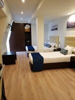 Habitación de hotel con dos camas, un armario y un escritorio.