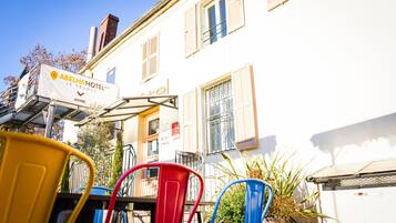 A hotel named "ABELHA HOTEL" with a signboard, outdoor seating with colorful chairs, and a potted plant.