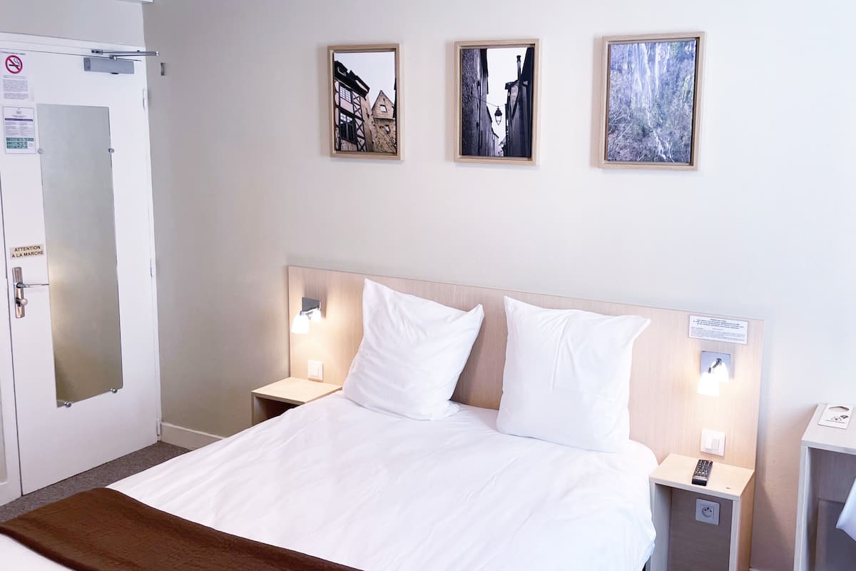 A hotel room with a bed, two bedside tables, a chair, and three framed pictures on the wall.