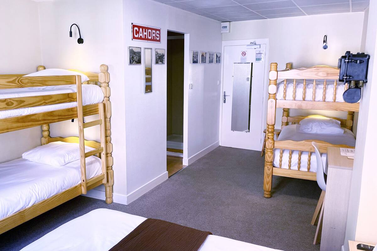 A bunk bed room with a sign reading "CAHORS" and a door leading to a bathroom.
