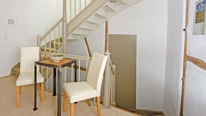 Una habitación con una escalera, una mesa de comedor con sillas y una puerta.