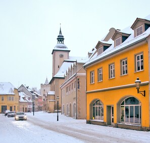 A snow-covered street with historic buildings, including a prominent tower with a clock. - Pension und Ferienwohnung Onkel Ernst (Naumburg)