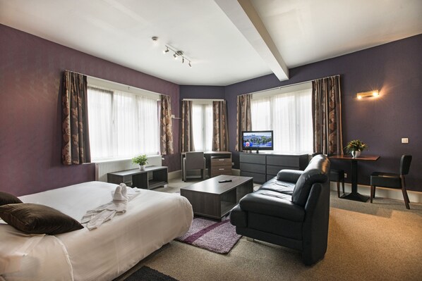 A modern hotel room with a bed, a sofa, a desk, and a television. - Hotel Cathedral Gent Centrum (Ghent)