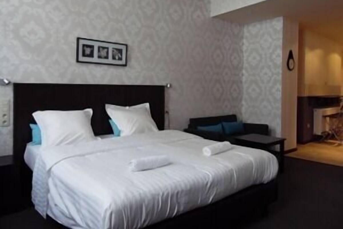 Habitación de hotel con una cama grande, una mesita de noche y un cuadro colgado en la pared.