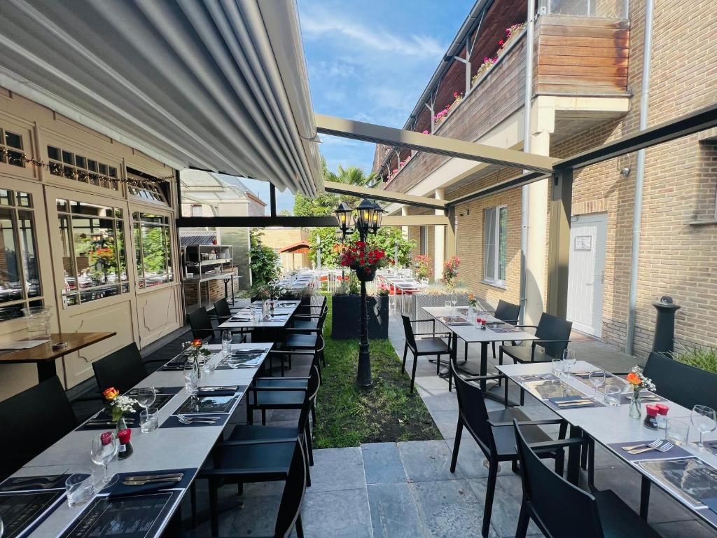 Een terras met tafels en stoelen, een pergola en uitzicht op de straat.