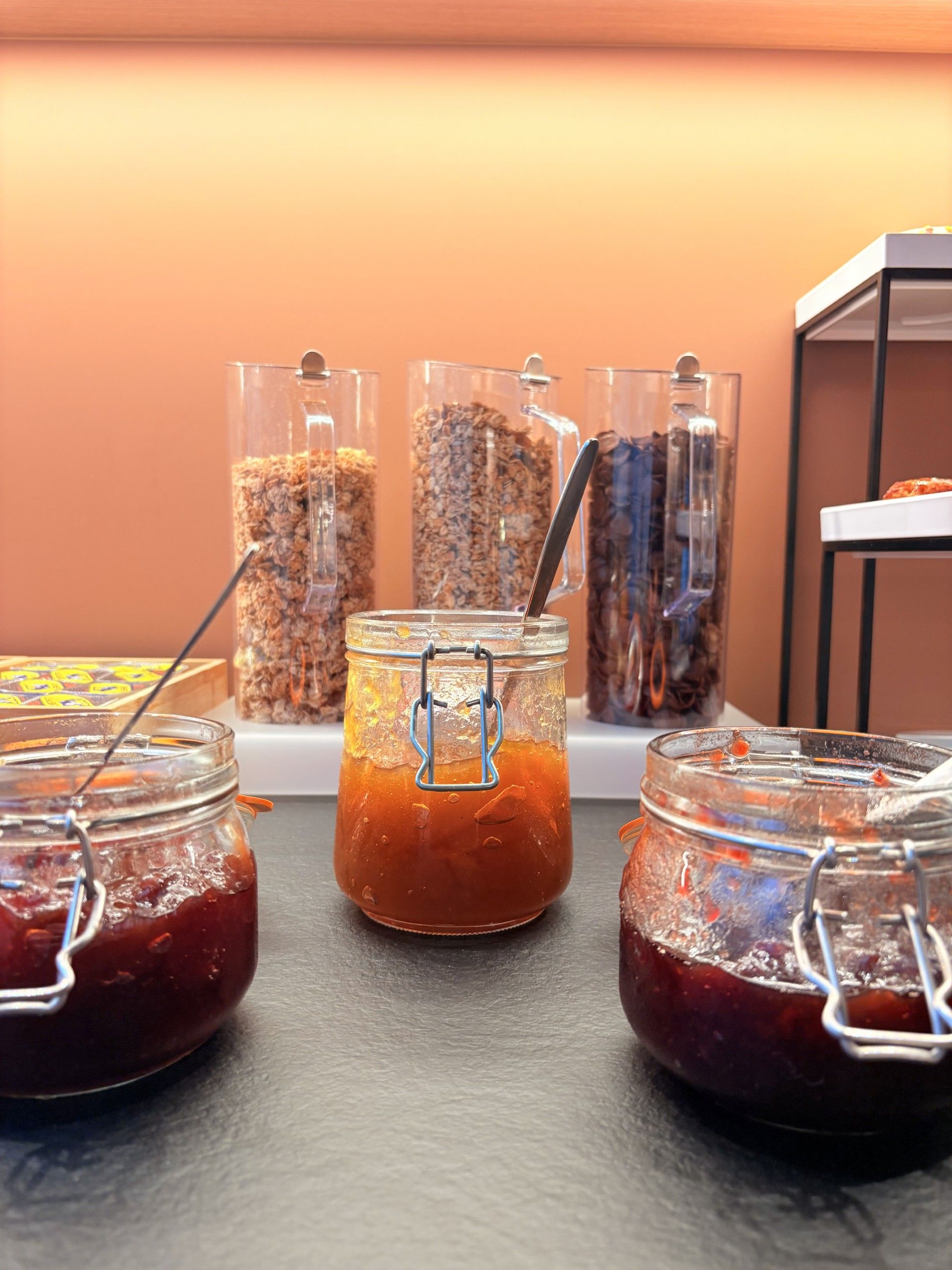 Diversos alimentos en recipientes, como frascos y dispensadores, probablemente en un entorno hotelero.