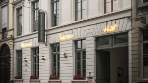 Un edificio histórico con una fachada clásica, múltiples ventanas y un letrero de neón que indica un hotel.