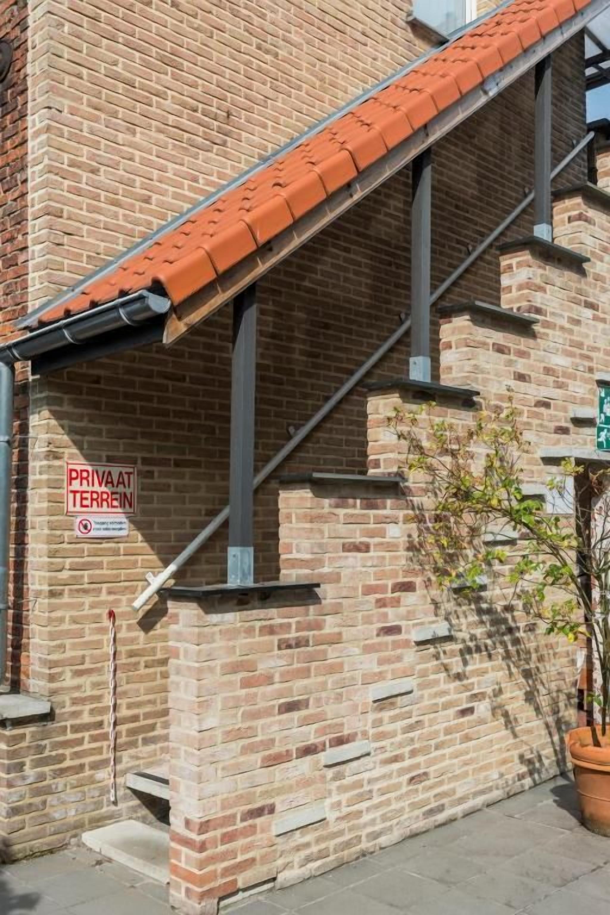 Een gebouw van baksteen met een rode pannendak en een bord dat aangeeft dat het privé-eigendom is.