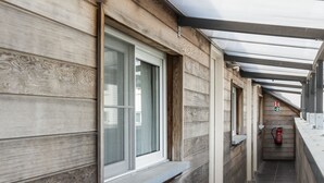 Un pasillo con paredes de paneles de madera, ventanas y piso de baldosas.
