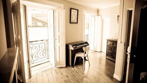 A room with a piano, a chair, and a cabinet. - Oasis Backpackers' Mansion Lisboa (Lisbon)