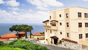 A multi-story building with a stone facade, a balcony, and a view of the sea. - Bülbül Yuvasi Boutique Hotel - Boutique Class (Foça)