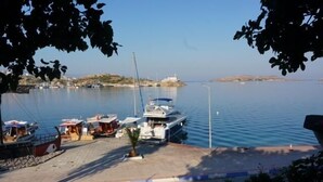 A marina with boats docked, a lighthouse in the background, and a clear sky. - Bülbül Yuvasi Boutique Hotel - Boutique Class (Foça)