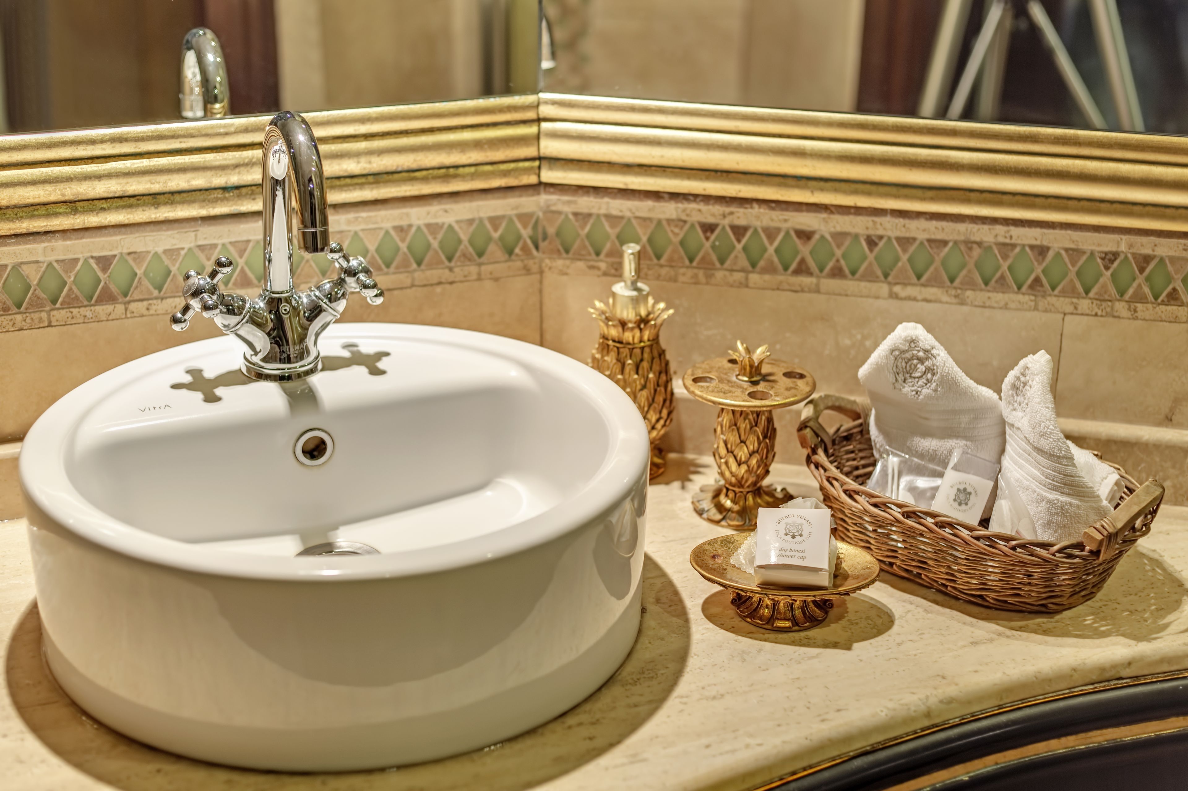 Un lavabo dans la salle de bain, doté d’un seul robinet, avec un miroir au-dessus et un panier décoratif contenant des serviettes, posé sur le comptoir.