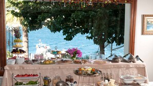 A buffet table with various food items and a view of the sea through a window. - Bülbül Yuvasi Boutique Hotel - Boutique Class (Foça)