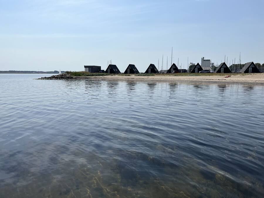 A row of beachside cottages with a clear view of the water and distant city skyline.