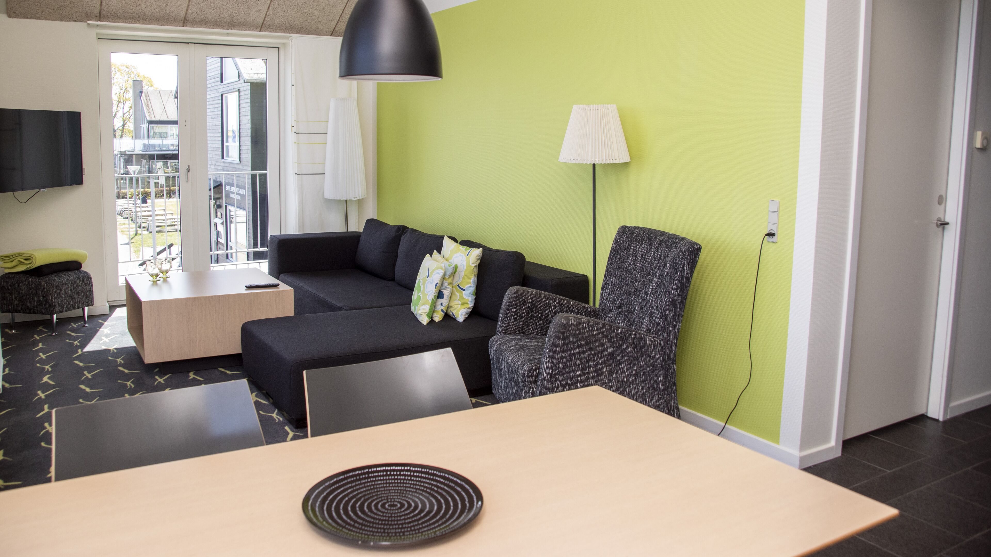 Ein modernes Wohnzimmer mit einer Couch, einem Sessel, einem kleinen Tisch und einem Fernseher.