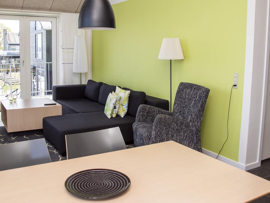 Ein modernes Wohnzimmer mit einer Couch, einem Sessel, einem kleinen Tisch und einem Fernseher.