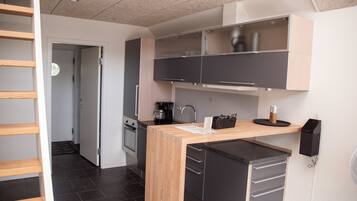 A compact kitchen with dark cabinets, a coffee maker, and a small refrigerator.