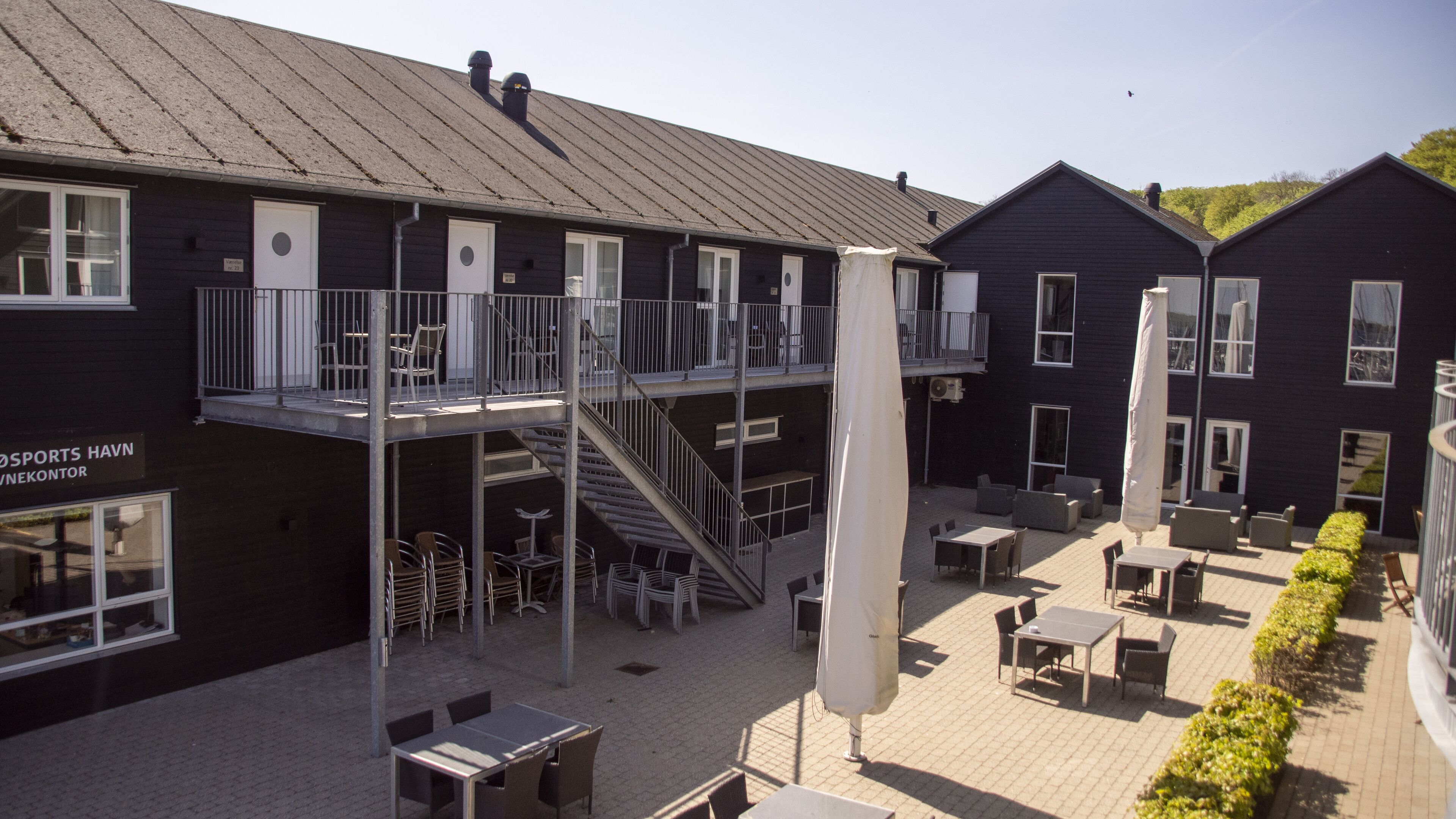 A building with a balcony, outdoor seating, and a staircase.
