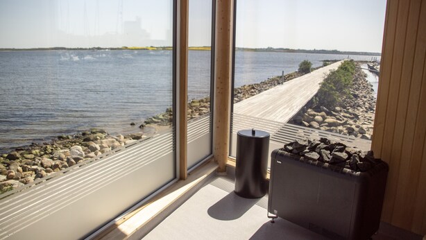 A view from a window overlooking a river, with a wooden deck and a radiator on the floor. - Hotel Strandtangen (Skive)