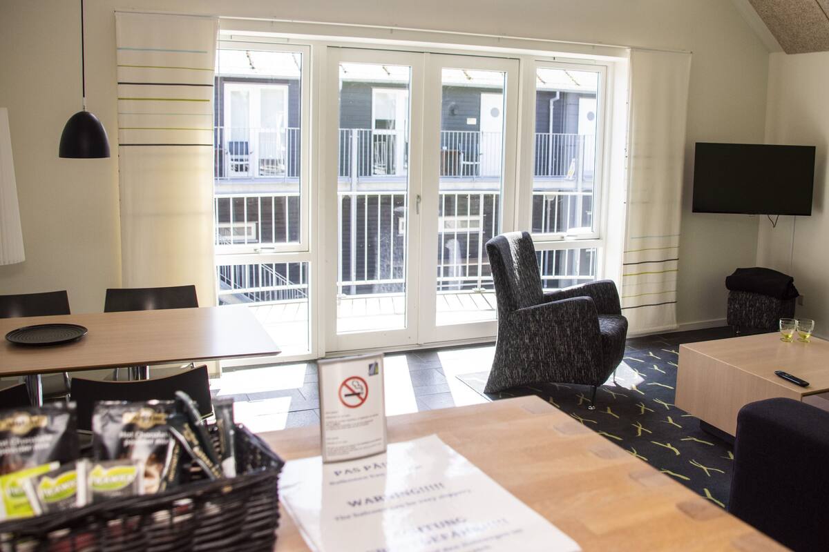 A hotel room with a balcony, a TV, and a dining area.