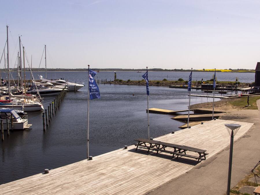 Un puerto deportivo con barcos amarrados, un muelle de madera y un edificio al fondo.