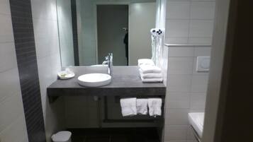 A modern bathroom with a round sink, a mirror, a towel rack, and a toilet.